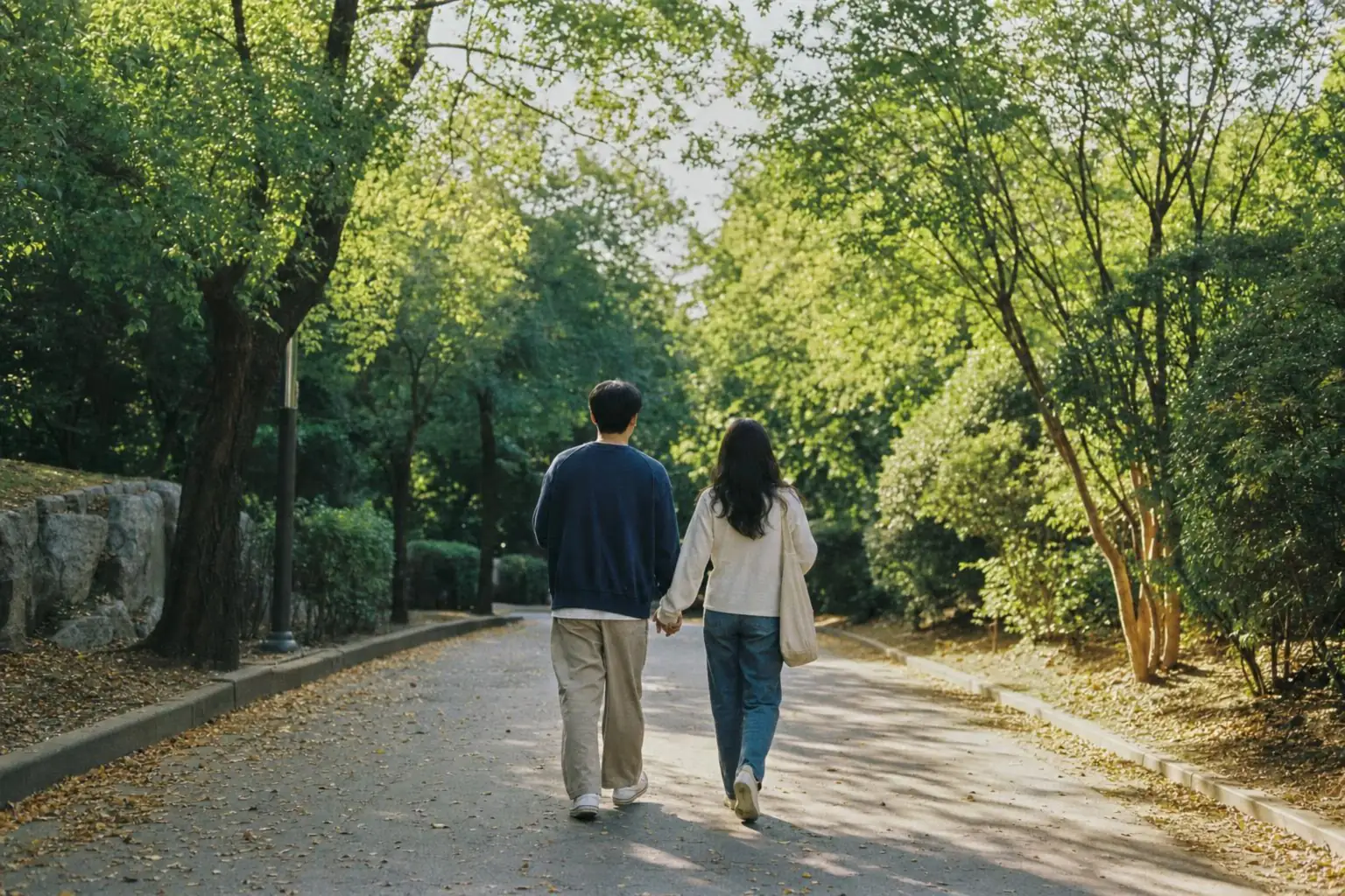 나무가 우거진 길을 손잡고 걷는 부부의 뒷모습